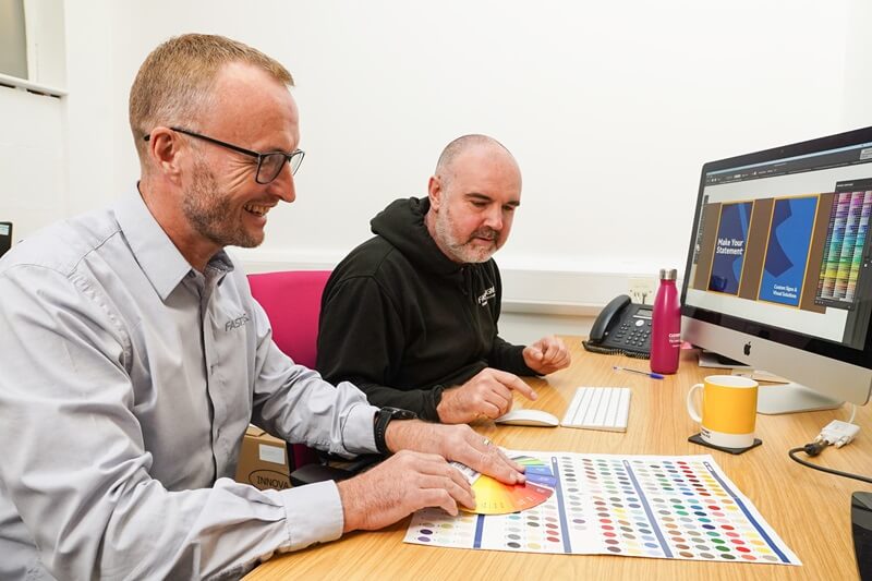 An image of Andy and a coworker designing signs.